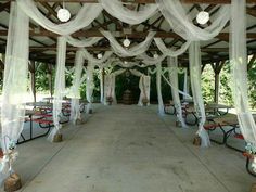 an outdoor wedding venue with white drapes and tables