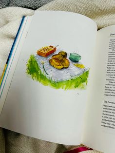 an open book sitting on top of a bed next to a cup and plate filled with food