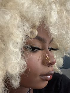 a close up of a person with blonde hair and piercings on her nose,