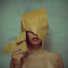 a shirtless woman holding a piece of paper over her face