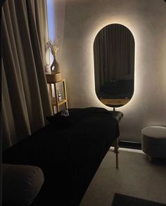 a dimly lit room with a round mirror on the wall and a black bed in front of it