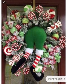 a christmas wreath with candy canes, stockings and an elf's head hanging from the front door