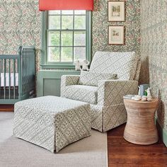 a baby's room with green walls and floral wallpaper on the walls, a rocking chair and footstool