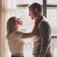 a man standing next to a woman near a window