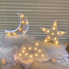 some white lights are sitting on top of a bed in the shape of a crescent and stars