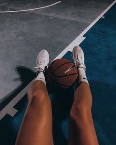 a person is sitting on the floor with a basketball in their hand and feet up