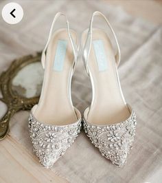 a pair of white high heeled shoes sitting on top of a wooden floor next to a mirror