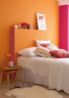 a bedroom with orange walls and white bedding