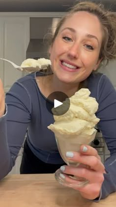 a woman eating an ice cream sundae with a spoon in her hand and smiling at the camera