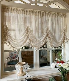 a window with curtains and flowers in front of it