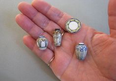 four small ceramic vases in the palm of someone's hand