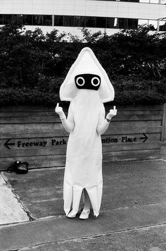 a person in a costume is standing on the side walk with their hands up and eyes wide open