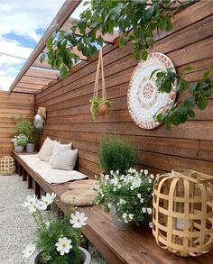 an outdoor seating area with potted plants and hanging planters on the wooden wall