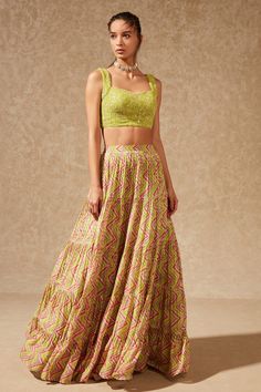 Green lehenga with all-over floral printed motifs, tiered hem and pleated detailing. Paired with embroidered blouse in sequin and bead work.
Component: 2
Pattern: Printed, Embroidered
Type Of Work: Chevron, Sequin, Beads
Neckline: Leaf neck
Sleeve Type: Sleeveless
Fabric: Lehenga: Georgette, Blouse: Silk, Dupatta: Tulle
Color: Green
Other Details: 
Tiered lehenga
Pleated detailing
Occasion: Mehendi and Haldi - Aza Fashions Attire Guide, Tiered Lehenga, Green Tulle, Fabric Skirt, Green Lehenga, Vacuum Storage, Blouse Silk, Georgette Blouse, Guest Attire