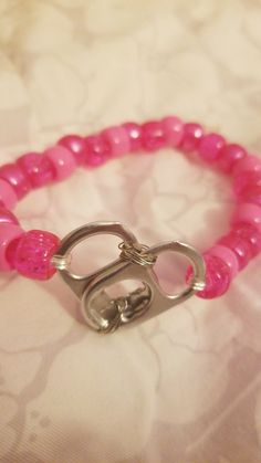 a pink beaded bracelet with silver clasps on a white fabric covered tablecloth