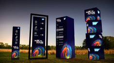 three tall black boxes with colorful graphics on them in front of a field at night