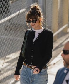 a woman in black sweater and jeans walking down the street