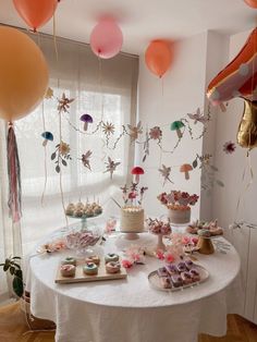 a table topped with lots of desserts and balloons in the shape of flowers on top of it