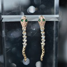 A ladies pair of 14 karat yellow gold snake dangle earrings set with 54 round brilliant cut diamonds having a total weight of .29 carats and 4 round emerald eyes having a total weight of .03 carats. Luxury White Gold Earrings With Diamond Eyes, Luxury Gold Earrings With Diamond Eyes, Yellow Gold Earrings With Diamond Eyes For Anniversary, Formal 14k Gold Earrings With Diamond Eyes, Yellow Gold Diamond Eyes Earrings For Anniversary, Anniversary Yellow Gold Earrings With Diamond Eyes, Luxury Handmade Gold Plated Earrings, Luxury Handmade Gold-plated Earrings, Handmade Gold Snake-shaped Earrings