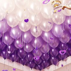 purple and white balloons are hanging from the ceiling