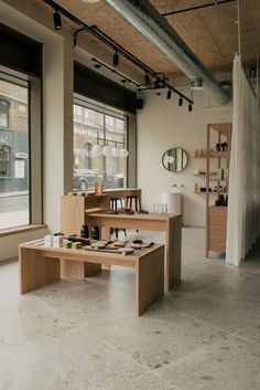 an empty room with tables and shelves in front of large windows that look out onto the street