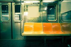 an empty subway car with yellow seats and graffiti on the wall next to it's doors