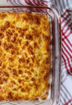 a casserole dish with cheese and meat in it on a red and white checkered cloth