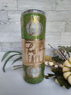 a green and gold glittered tumbler next to flowers