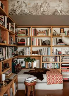 an open book with bookshelves full of books and pictures on the wall behind it