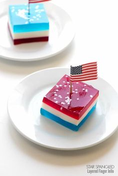 two small patriotic desserts on white plates with american flag flags sticking out of them