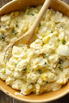 a wooden spoon in a bowl filled with potato salad