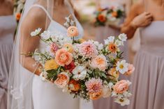 the bridesmaids are holding their bouquets with orange and white flowers in them