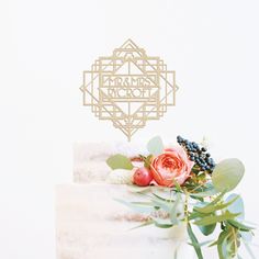 a close up of a wedding cake with flowers on the top and an ornament above it