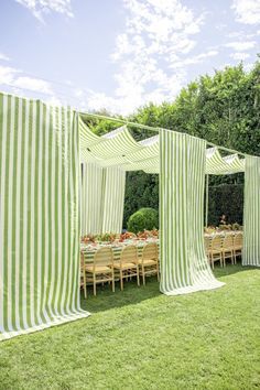 a green and white striped tent set up for an outdoor party with tables and chairs