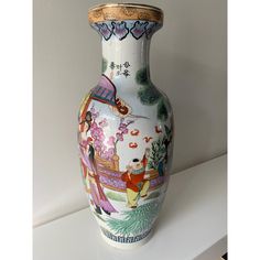 a white vase with colorful designs on it sitting on a shelf next to a wall