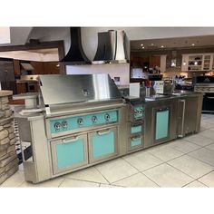 an outdoor kitchen with stainless steel appliances and blue glass doors on the cabinets, stoves and counter tops