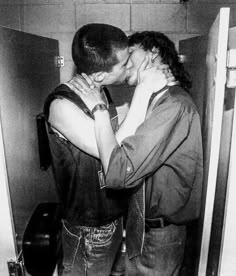 black and white photograph of two people kissing each other in an elevator stall with the door open