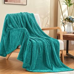 a teal blanket draped over a chair in a room with wood floors and walls