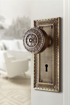 an ornate door handle on the side of a white door with a gold keyhole