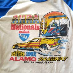 a white and blue baseball shirt with an image of a yellow car on the front