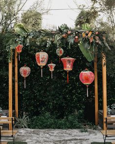 an outdoor ceremony with red lanterns and greenery