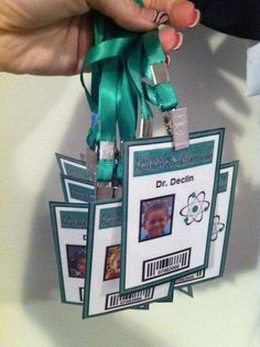 someone is holding up some id badges with green ribbons on them, and they are attached to each other