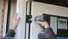 a man is using a driller to fix a door handle on a brick building