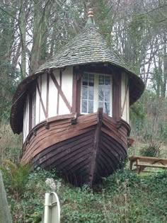 an old wooden boat sitting in the woods next to a building with a round roof