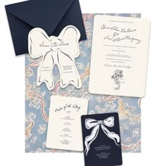 the wedding stationery is laid out on top of an ornate blue and white paper