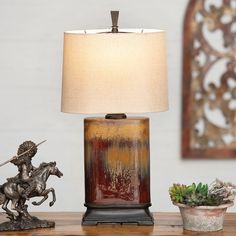 a table lamp sitting on top of a wooden table next to a potted plant