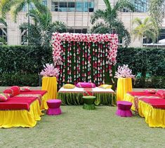 an outdoor area with tables and chairs covered in red, yellow and pink cloths