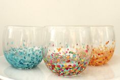 three wine glasses filled with confetti and sprinkles on a table