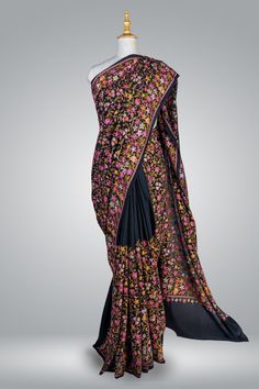 Black Crepe Saree All Over Embroidered, Elegant Women Saree With Aari Embroidery, Party Wear Saree Immerse yourself in the rich heritage of Kashmiri craftsmanship with this exquisite Chinar Pure Crepe Saree adorned with intricate hand aari embroidery. The luxurious black crepe fabric serves as a canvas for the exceptional artistry of the skilled artisans of Kashmir, who dedicate countless hours to create the breathtakingly beautiful motifs adorning this saree. The centerpiece of this saree is the heavy multicolour aari hand embroidery along the border and the pallu, showcasing the iconic Chinar design. The Chinar, or maple leaf, holds a deep cultural significance in Kashmir, representing the region's captivating natural beauty and storied history. The harmonious blend of green, red, and br Transitional Pre-draped Saree With Floral Embroidery, Embroidered Saree For Reception And Transitional Seasons, Transitional Embroidered Saree For Reception, Transitional Reception Saree With Embroidery, Transitional Floral Embroidered Saree, Traditional Drape Salwar Kameez With Multicolor Embroidery For Reception, Traditional Salwar Kameez With Multicolor Embroidery For Reception, Transitional Bollywood Style Pre-draped Saree With Floral Embroidery, Transitional Anarkali Saree With Floral Embroidery