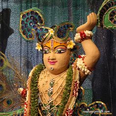 an elaborately decorated mask with peacock feathers on it's head and hands in the air